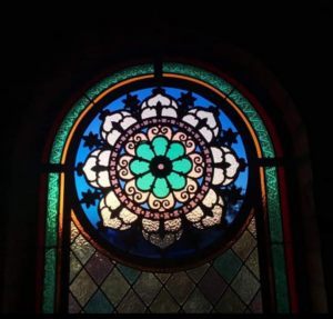 colourful stained glass window behind iron grill